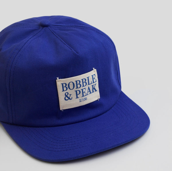 Front view of Bobble and Peak Drop 003 Navy Blue baseball cap with signature logo