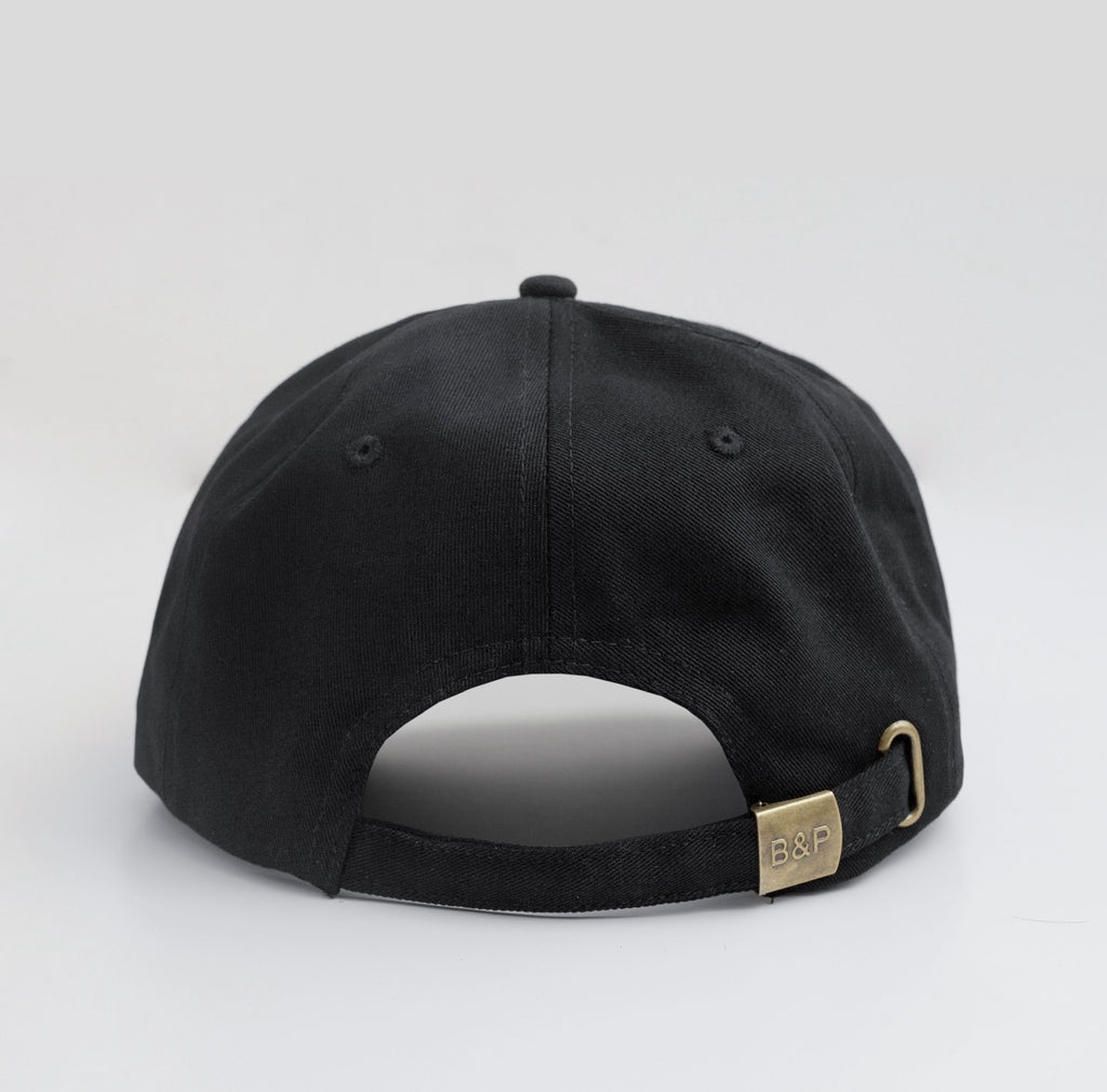 Black cap with a gold logo on a light grey background