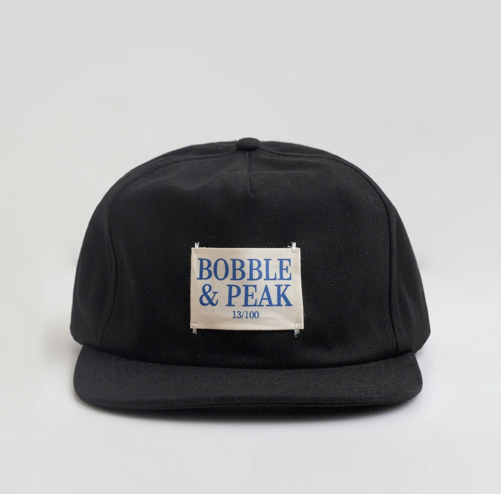 Black cap with 'Bobble & Peak' label on a light gray background